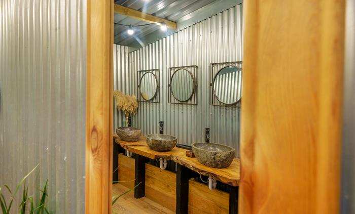 Rustic-style washroom with three granite basins and mirrors